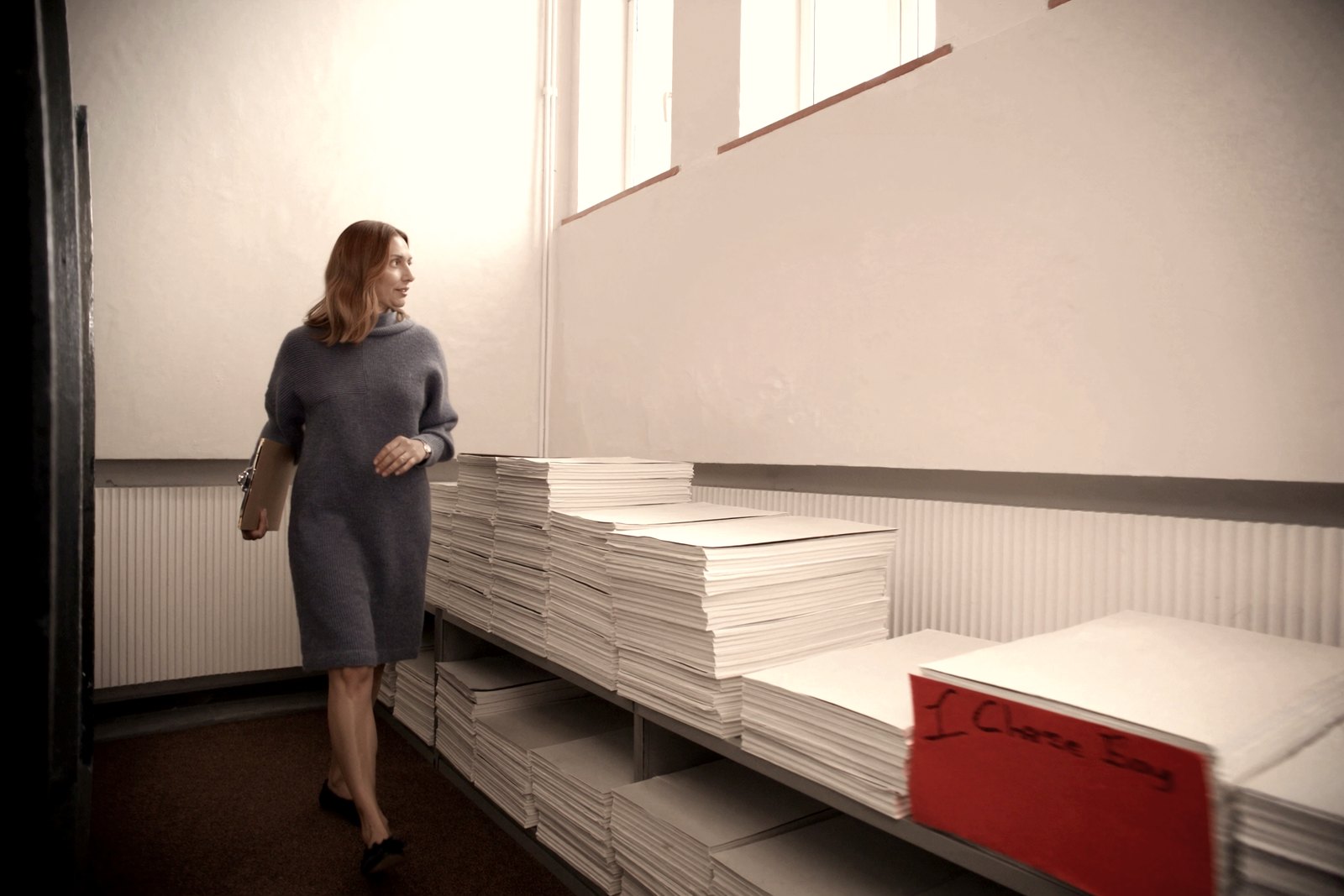 A woman with a clipboard counting what is held on archive shelving