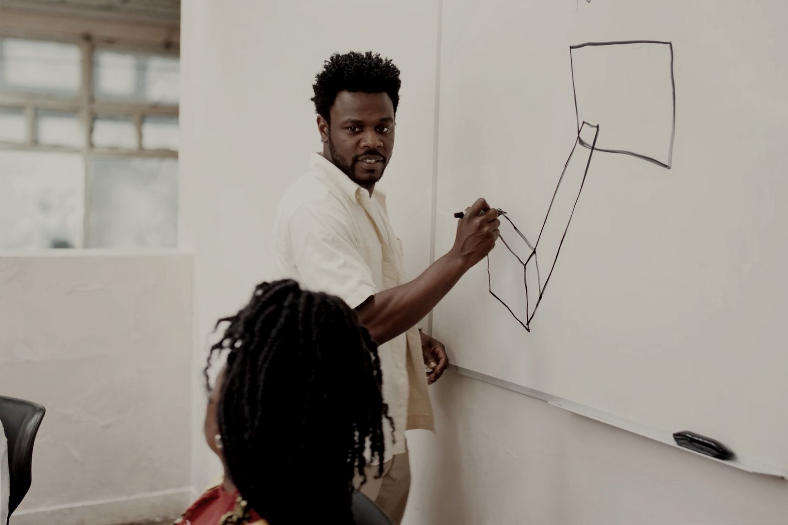 A document controller sketching a simple process diagram on a whiteboard