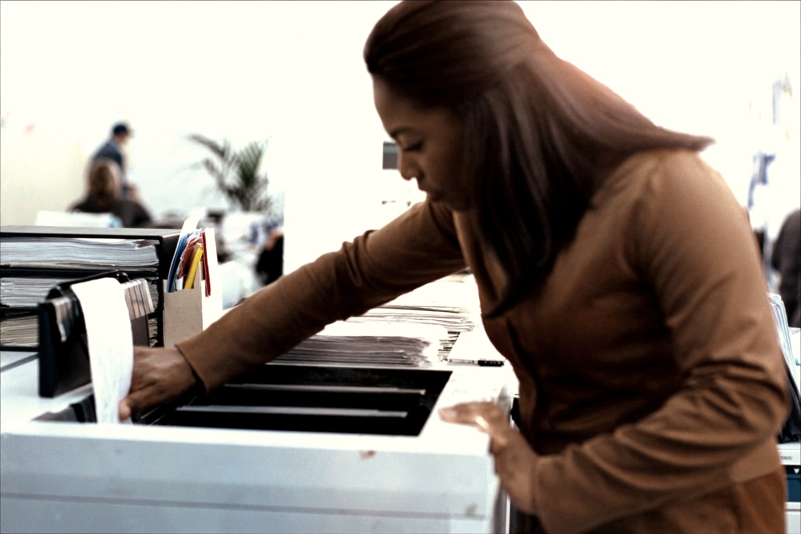A woman feeding loose documents into a production scanner