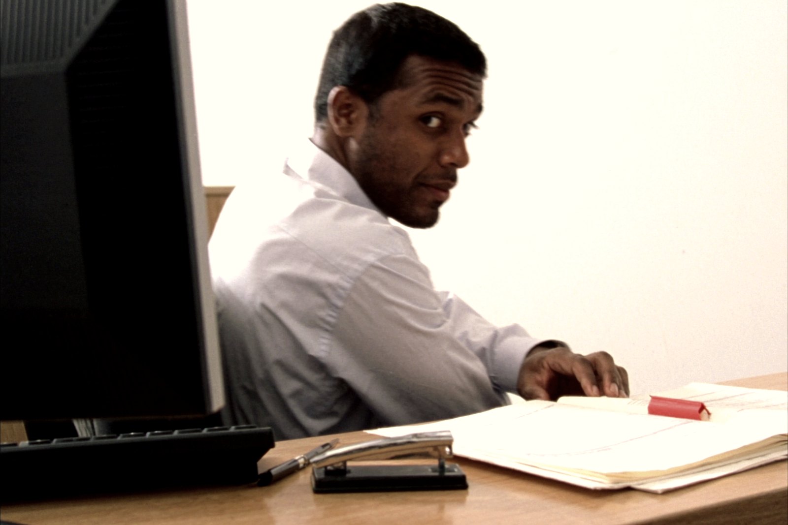 A document controller at a desk checking a record against an open folder